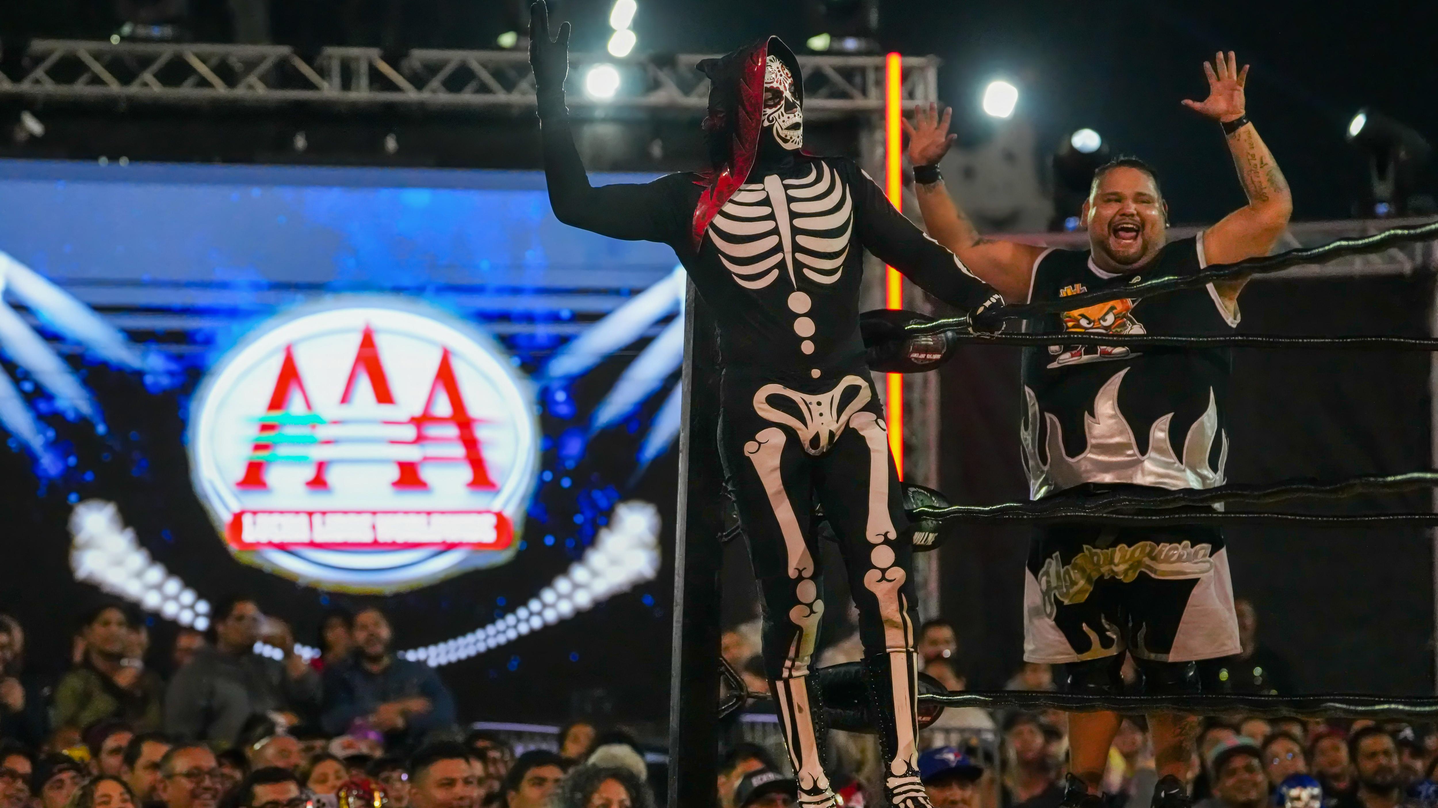 La Parka and Nino Hamburguesa celebrate in the ring, soaking...